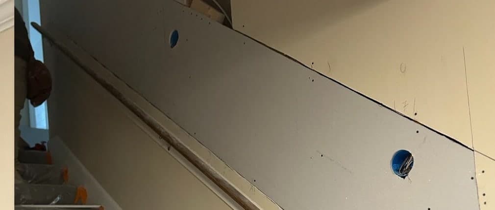 New drywall hung and screwed off along the stairwell wall, cut around the electrical box, by Drywall & Remodeling ETC.